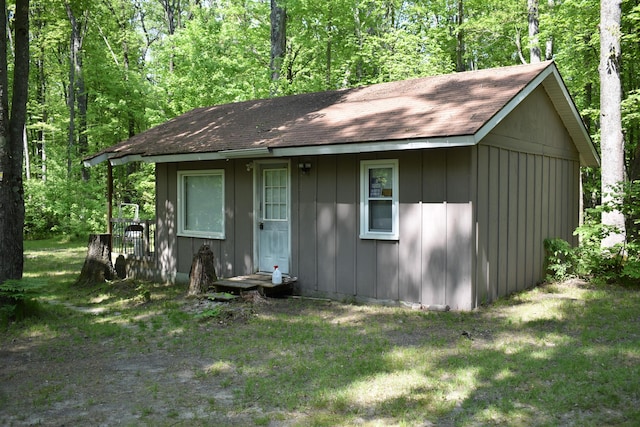 2186 88th St, Bitely, MI 49309 - view of front of home with board and batten siding, a shingled roof, a front yard, and a view of trees