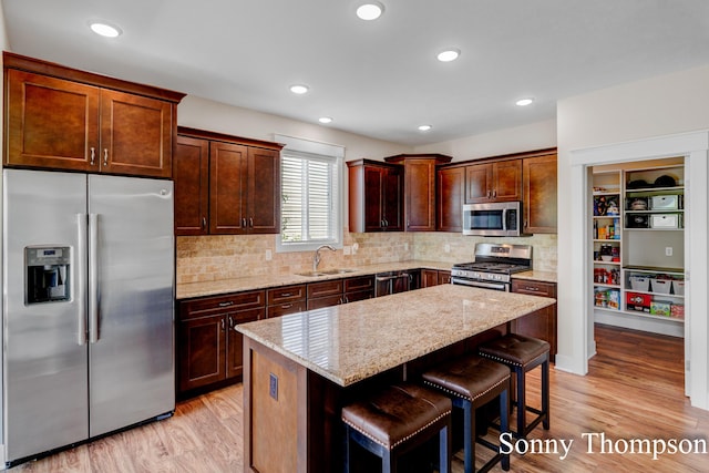 3912 Preserve Dr NE Unit 44, Belmont, MI 49306 - kitchen with stainless steel appliances, a sink, light wood finished floors, light stone counters, and a center island