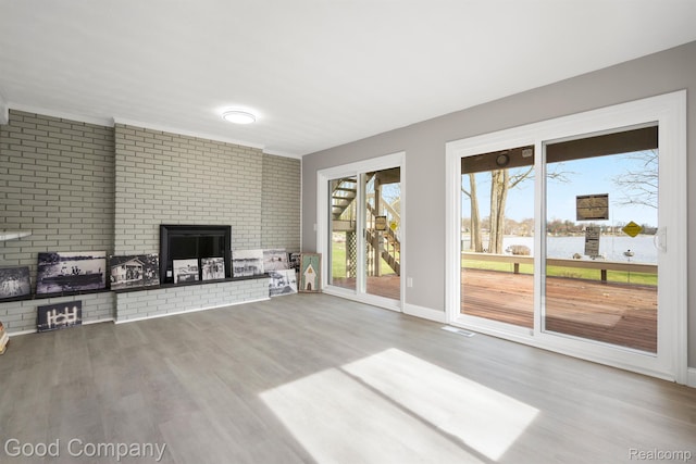 3501 Mann Rd, Clarkston, MI 48346 - unfurnished living room with a brick fireplace, wood finished floors, a water view, baseboards, and brick wall