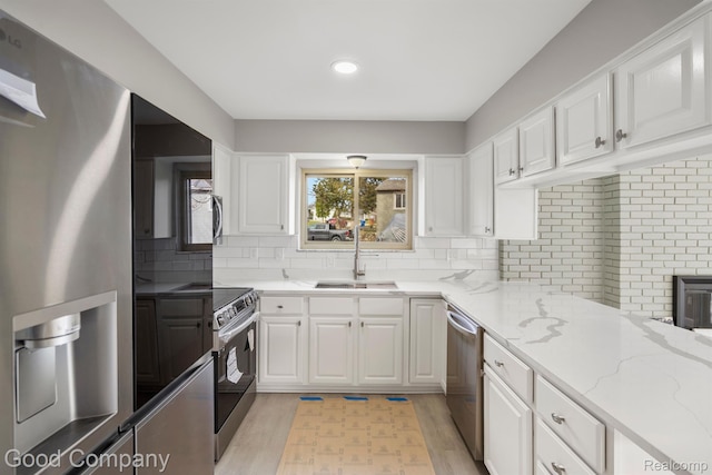 3501 Mann Rd, Clarkston, MI 48346 - kitchen with a sink, stainless steel appliances, white cabinetry, backsplash, and light stone counters