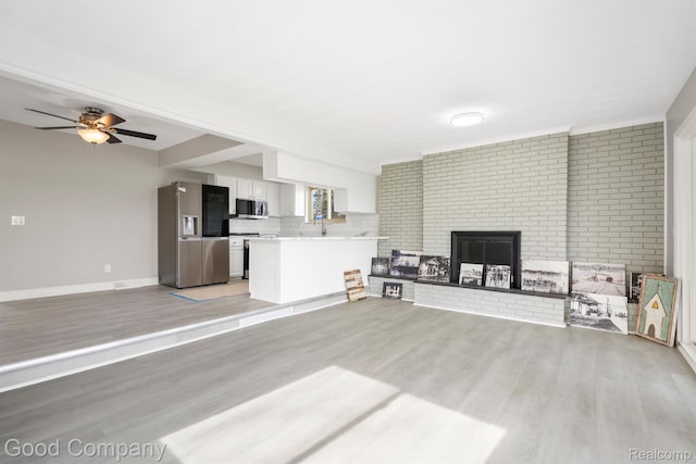 3501 Mann Rd, Clarkston, MI 48346 - living room with light wood finished floors, ceiling fan, a brick fireplace, and baseboards