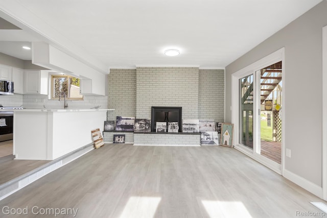 3501 Mann Rd, Clarkston, MI 48346 - living area featuring light wood finished floors, a brick fireplace, and baseboards