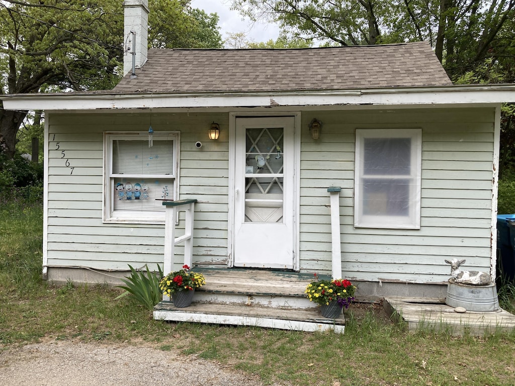 15567 Comstock St, Grand Haven, MI 49417 - property entrance featuring a shingled roof and a chimney