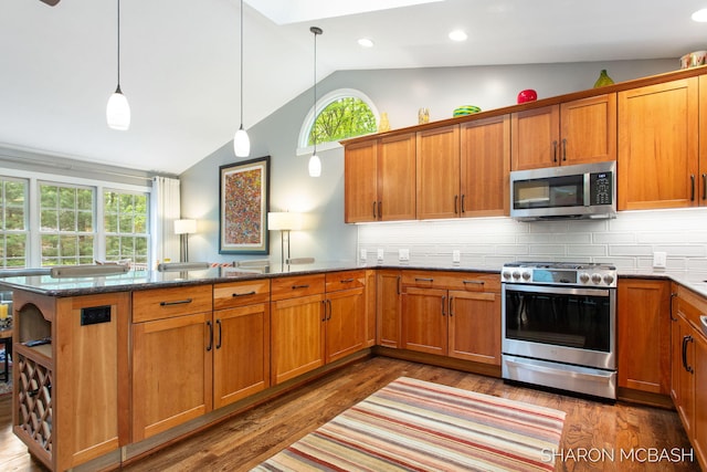 3348 Clearview Ln, Saugatuck, MI 49453 - kitchen featuring appliances with stainless steel finishes, lofted ceiling, a peninsula, brown cabinets, and wood finished floors