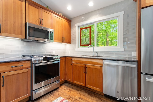 3348 Clearview Ln, Saugatuck, MI 49453 - kitchen featuring stainless steel appliances, a sink, dark stone countertops, decorative backsplash, and brown cabinets