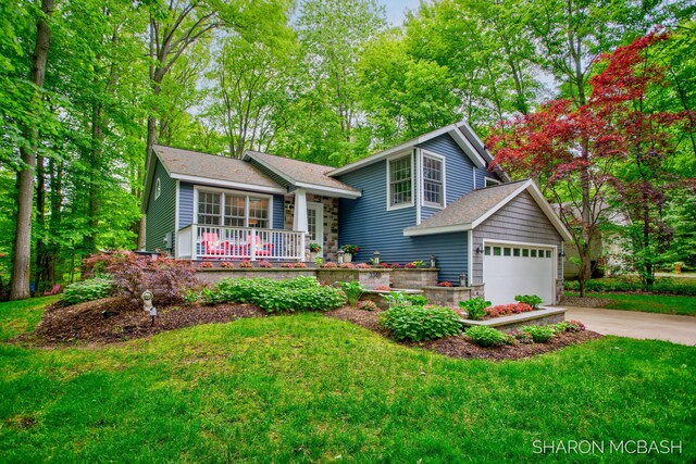 3348 Clearview Ln, Saugatuck, MI 49453 - split level home featuring a porch, concrete driveway, a front yard, an attached garage, and roof with shingles