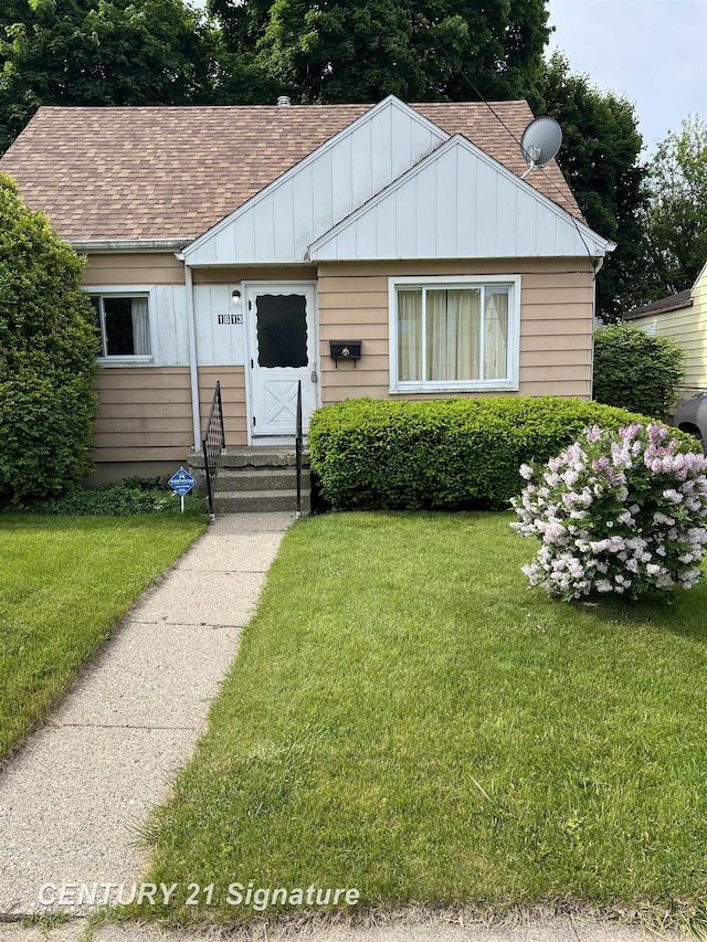 1613 Waldman Ave, Flint, MI 48507 - bungalow-style house with board and batten siding, entry steps, a front yard, and a shingled roof