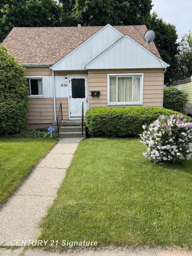 1613 Waldman Ave, Flint, MI 48507 - bungalow-style home featuring board and batten siding, a front yard, roof with shingles, and entry steps