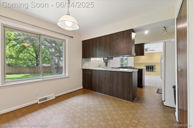 5045 Bronco Dr, Clarkston, MI 48346 - kitchen featuring dark brown cabinets, light countertops, a peninsula, and freestanding refrigerator
