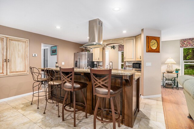 731 13 Mile Rd NW, Sparta, MI 49345 - kitchen with appliances with stainless steel finishes, island exhaust hood, a kitchen bar, light stone countertops, and recessed lighting