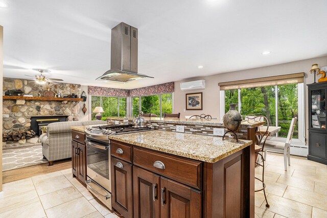 731 13 Mile Rd NW, Sparta, MI 49345 - kitchen with island range hood, a wall unit AC, gas range, a kitchen breakfast bar, and a center island