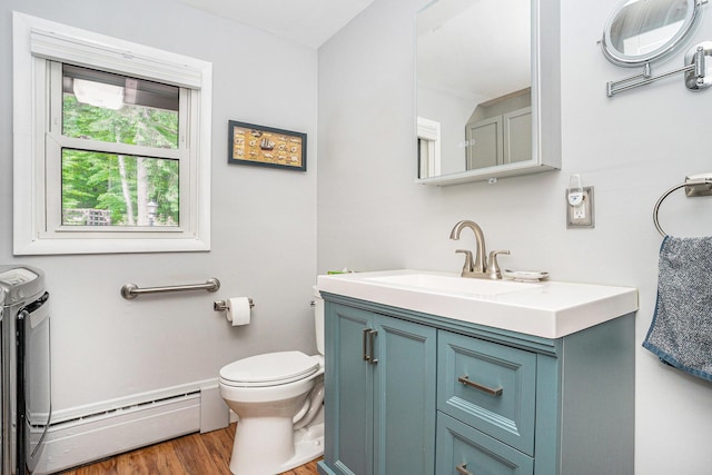 731 13 Mile Rd NW, Sparta, MI 49345 - bathroom featuring a baseboard heating unit, independent washer and dryer, wood finished floors, toilet, and vanity