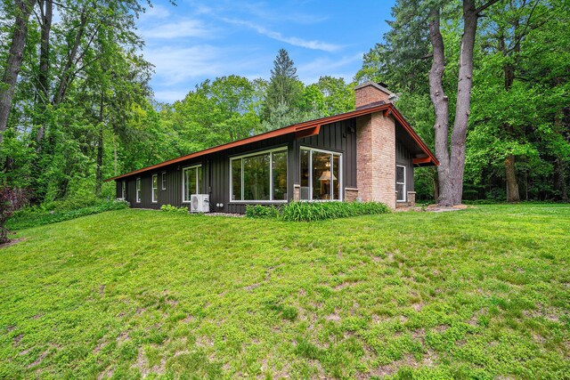 731 13 Mile Rd NW, Sparta, MI 49345 - rear view of property featuring a chimney, board and batten siding, a yard, and a cooling unit