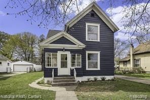 222 N Gorham St, Jackson, MI 49202 - view of front of property with entry steps, a detached garage, a front yard, and an outdoor structure
