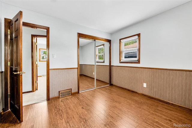 26500 Grant St, Saint Clair Shores, MI 48081 - unfurnished bedroom featuring a wainscoted wall, wood finished floors, a closet, and baseboards