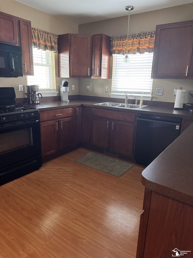 2446 8th St, Wyandotte, MI 48192 - kitchen with black appliances, a sink, dark countertops, and light wood-style floors