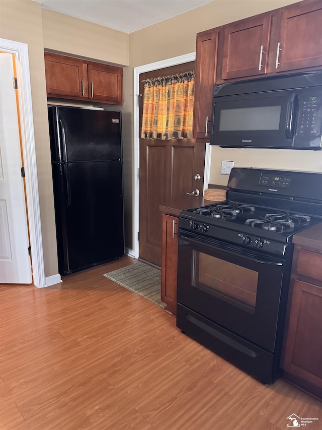 2446 8th St, Wyandotte, MI 48192 - kitchen with black appliances, light wood-type flooring, dark countertops, and baseboards