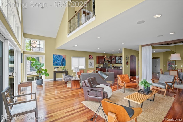 15496 Bealfred Dr, Fenton, MI 48430 - living room featuring arched walkways, light wood-style flooring, healthy amount of natural light, and a towering ceiling