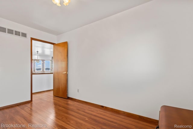 2995 Venice, Highland, MI 48356 - spare room with wood finished floors, baseboards, and a chandelier