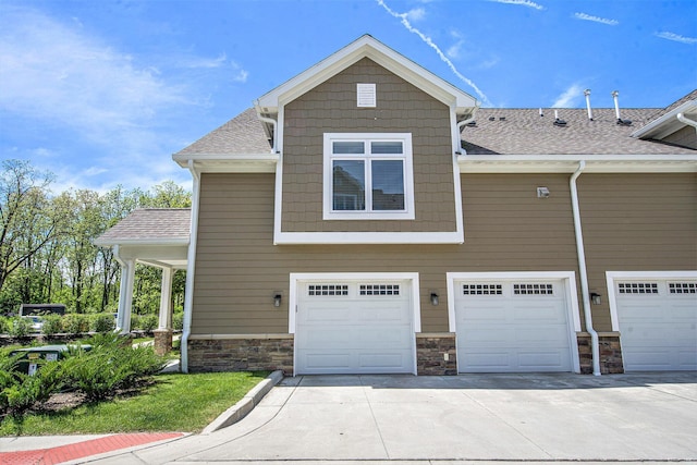 603 Woodland, Dexter, MI 48130 - view of side of home with concrete driveway, an attached garage, a shingled roof, and stone siding
