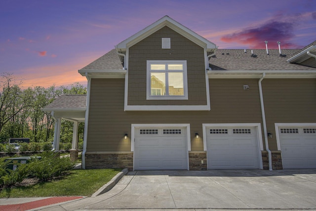 603 Woodland, Dexter, MI 48130 - view of front of house featuring a garage, driveway, stone siding, and roof with shingles