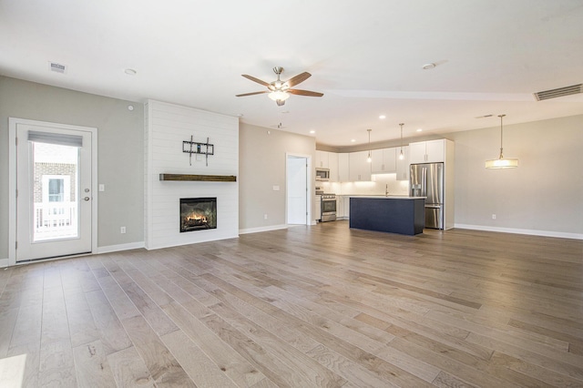 603 Woodland, Dexter, MI 48130 - unfurnished living room with a ceiling fan, light wood-type flooring, baseboards, recessed lighting, and a large fireplace