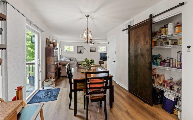 5855 Larson Ln, Muskegon, MI 49444 - dining area with wood finished floors, a barn door, and a chandelier