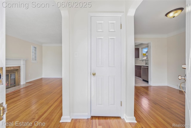 21167 Lancaster St, Grosse Pointe Woods, MI 48225 - hallway featuring light wood-style floors, arched walkways, a sink, and baseboards