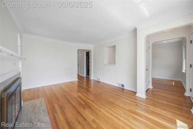 21167 Lancaster St, Grosse Pointe Woods, MI 48225 - unfurnished living room with a fireplace, arched walkways, light wood-style floors, and baseboards