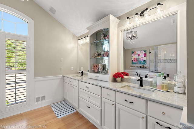 1707 Mountain Ash Dr, West Bloomfield, MI 48324 - bathroom with double vanity, wood finished floors, wainscoting, tiled shower, and lofted ceiling