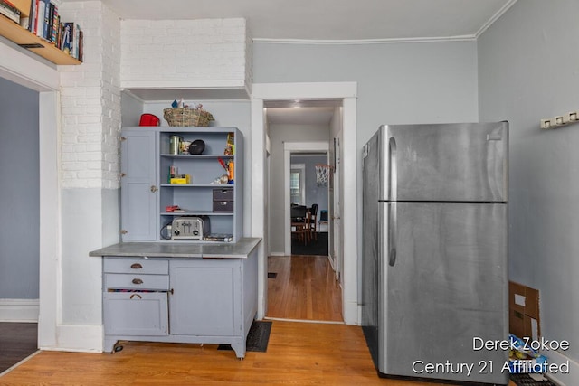 1237 Wealthy St SE, Grand Rapids, MI 49506 - kitchen with freestanding refrigerator, stainless steel counters, light wood-style floors, open shelves, and ornamental molding