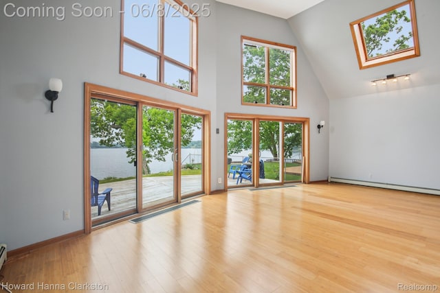 2734 Silverside Rd, Waterford, MI 48328 - unfurnished living room with high vaulted ceiling, a baseboard radiator, a skylight, and wood finished floors