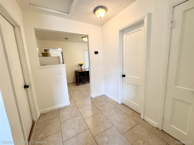 5689 Cornell St, Dearborn Heights, MI 48125 - corridor featuring a textured ceiling, light tile patterned floors, baseboards, and attic access