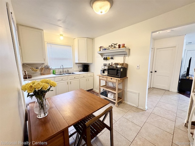 5689 Cornell St, Dearborn Heights, MI 48125 - kitchen with a sink, stainless steel microwave, light countertops, light tile patterned floors, and white cabinets