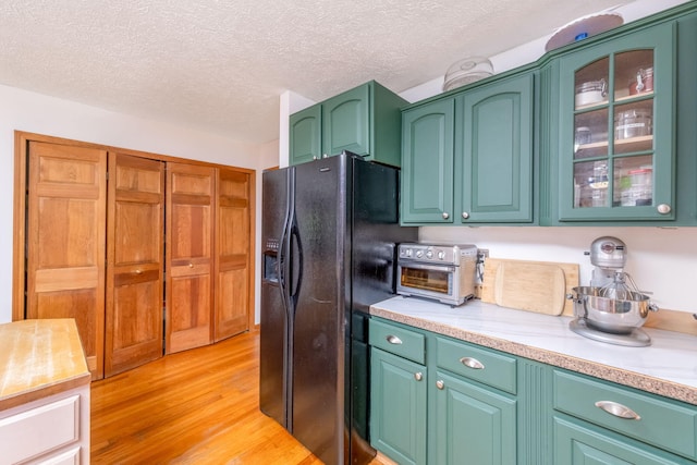 4300 Holton-Duck Lake Rd, Twin Lake, MI 49457 - kitchen with black refrigerator with ice dispenser, light wood-style flooring, light countertops, a textured ceiling, and glass insert cabinets