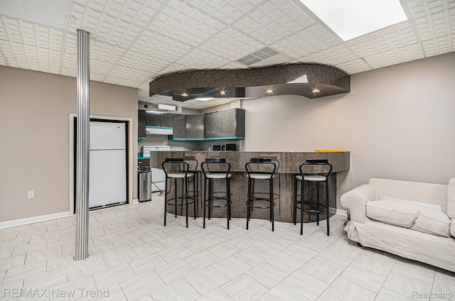2337 Horseshoe Dr, West Bloomfield, MI 48322 - kitchen with freestanding refrigerator, under cabinet range hood, a breakfast bar area, and a peninsula