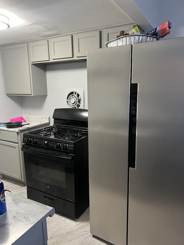 13990 Lauder St, Detroit, MI 48227 - kitchen featuring black gas stove, freestanding refrigerator, light marble finish floors, and light countertops