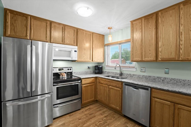9939 Hamilton St, Michigan, MI 48111 - kitchen featuring stainless steel appliances, a sink, wood finished floors, light stone counters, and brown cabinetry