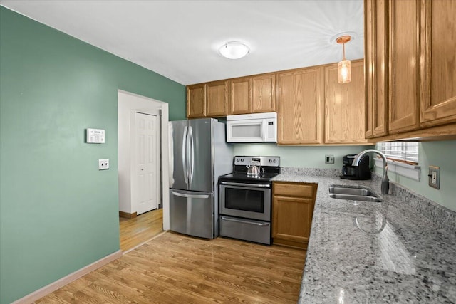 9939 Hamilton St, Michigan, MI 48111 - kitchen featuring appliances with stainless steel finishes, a sink, light stone countertops, light wood-type flooring, and brown cabinetry