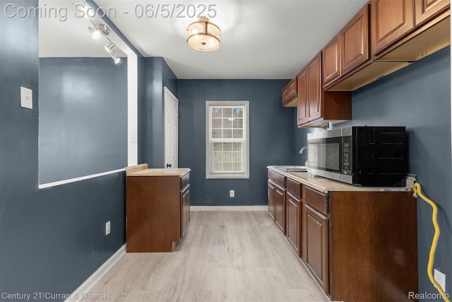 16509 Woodingham Dr, Detroit, MI 48221 - kitchen with light wood-style flooring, stainless steel microwave, light countertops, a sink, and baseboards