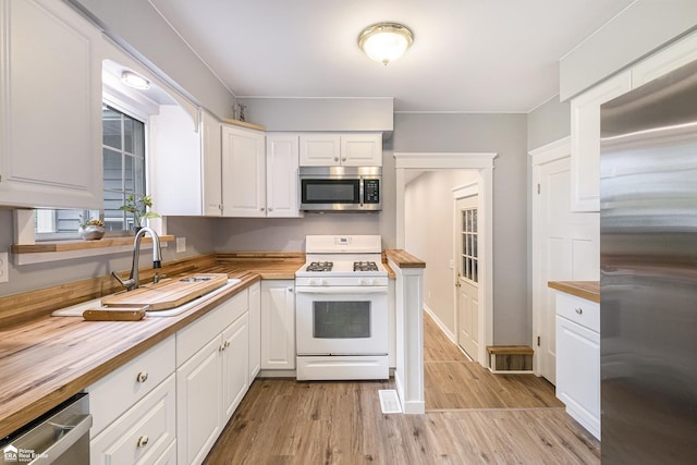 10207 Frances Rd, Flushing, MI 48433 - kitchen featuring appliances with stainless steel finishes, wooden counters, white cabinets, and a sink