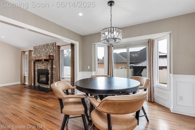 52657 Creekside Dr, Chesterfield, MI 48047 - dining space featuring a chandelier, a wainscoted wall, light wood-type flooring, a fireplace, and a decorative wall