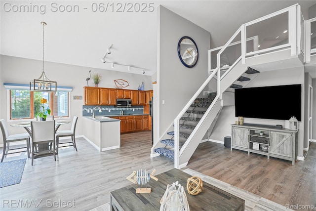 7457 Haviland Beach Dr, Argentine, MI 48451 - living area with stairs, light wood-type flooring, track lighting, baseboards, and vaulted ceiling