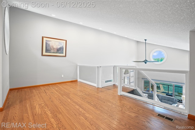 7457 Haviland Beach Dr, Argentine, MI 48451 - unfurnished room with a textured ceiling, wood finished floors, baseboards, recessed lighting, and high vaulted ceiling