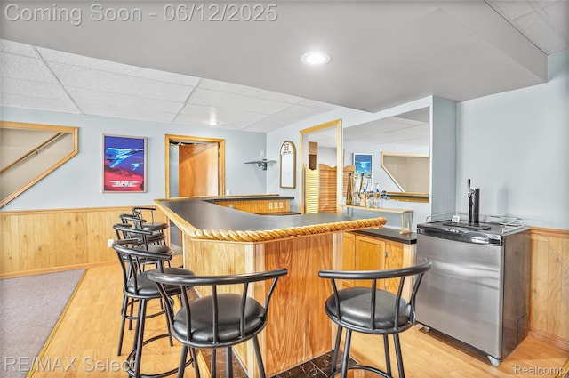 7457 Haviland Beach Dr, Argentine, MI 48451 - indoor wet bar featuring light wood finished floors, a paneled ceiling, a wainscoted wall, fridge, and wooden walls