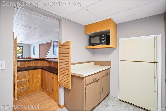7457 Haviland Beach Dr, Argentine, MI 48451 - kitchen featuring freestanding refrigerator, a drop ceiling, black microwave, light wood-style flooring, and open shelves