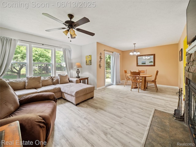 8907 Mccoll Side Rd, Brighton, MI 48116 - living area featuring wood finished floors, plenty of natural light, a stone fireplace, and a chandelier