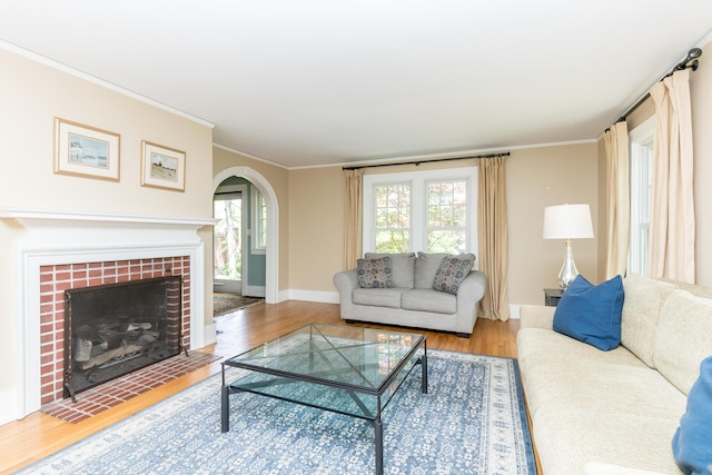 2430 Geddes Ave, Ann Arbor, MI 48104 - living area featuring arched walkways, wood finished floors, a tiled fireplace, baseboards, and crown molding