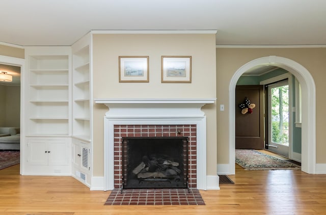 2430 Geddes Ave, Ann Arbor, MI 48104 - unfurnished living room with a fireplace, light wood-style flooring, ornamental molding, built in features, and arched walkways