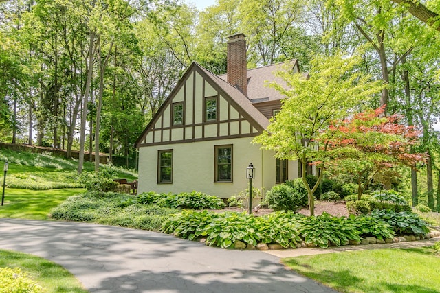2430 Geddes Ave, Ann Arbor, MI 48104 - view of home's exterior with stucco siding, a chimney, roof with shingles, and a lawn